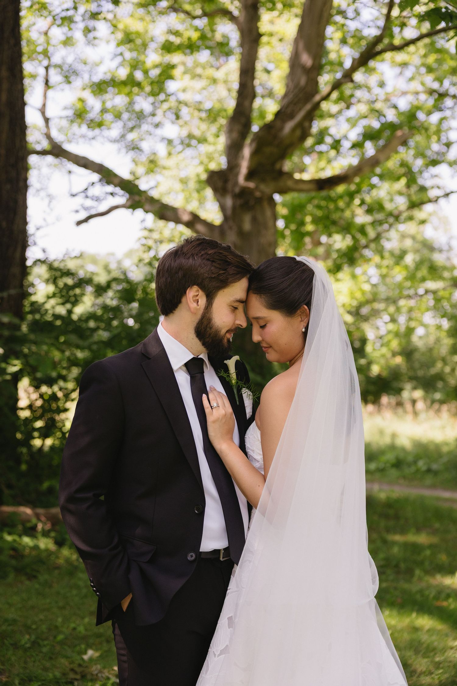 Bride and groom sharing a tender moment forehead to forehead outdoors at Wadsworth Homestead in Geneseo, NY.