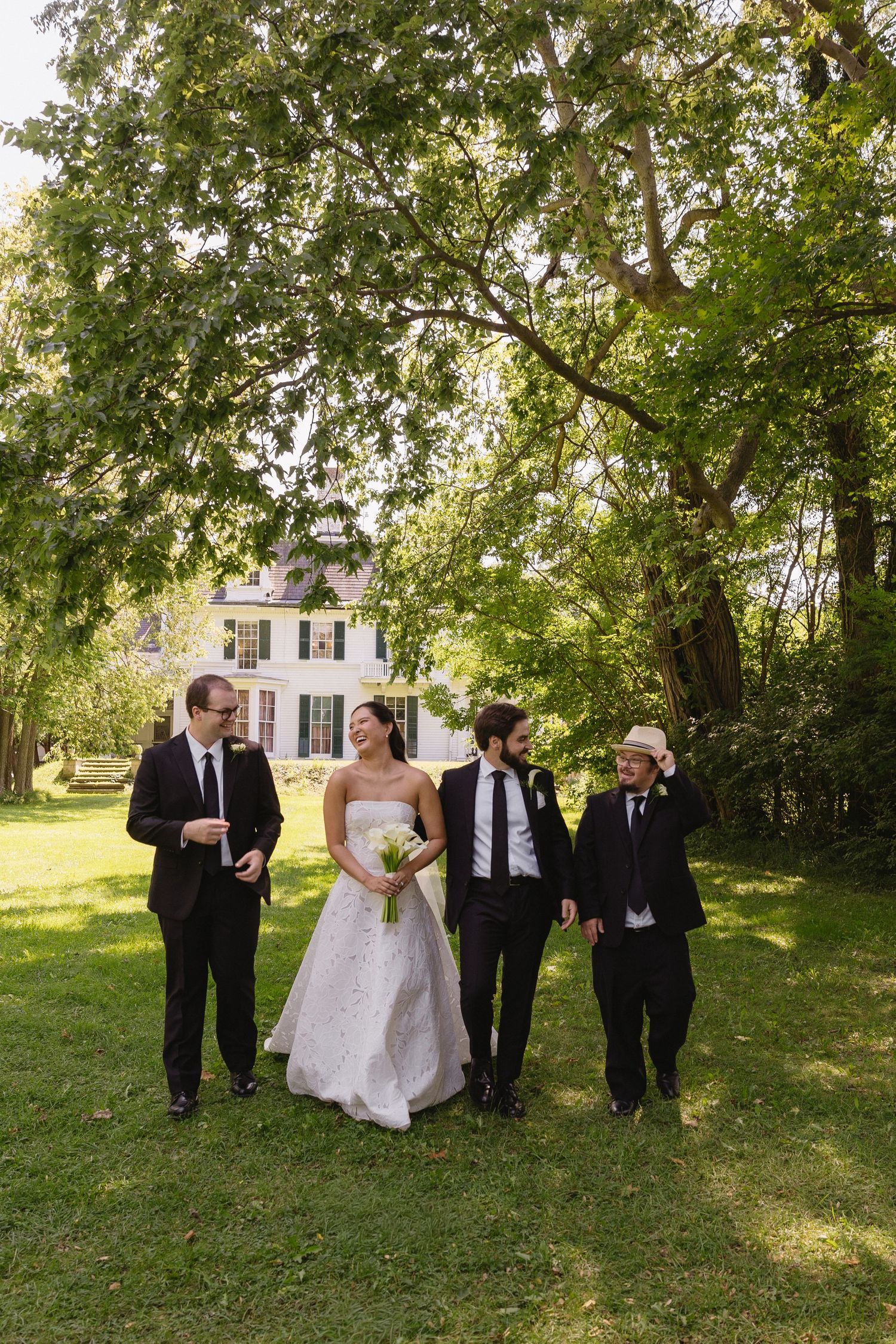 Bride and groom walking on lawn with groomsmen at Wadsworth Homestead in Geneseo, NY.