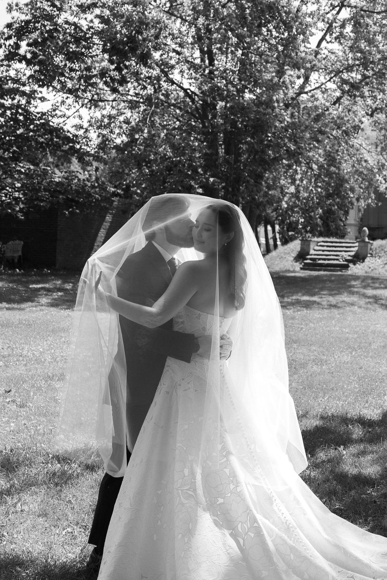 Groom kissing a bride under her veil outdoors at the historic Wadsworth Homestead wedding venue in Geneseo, New York.