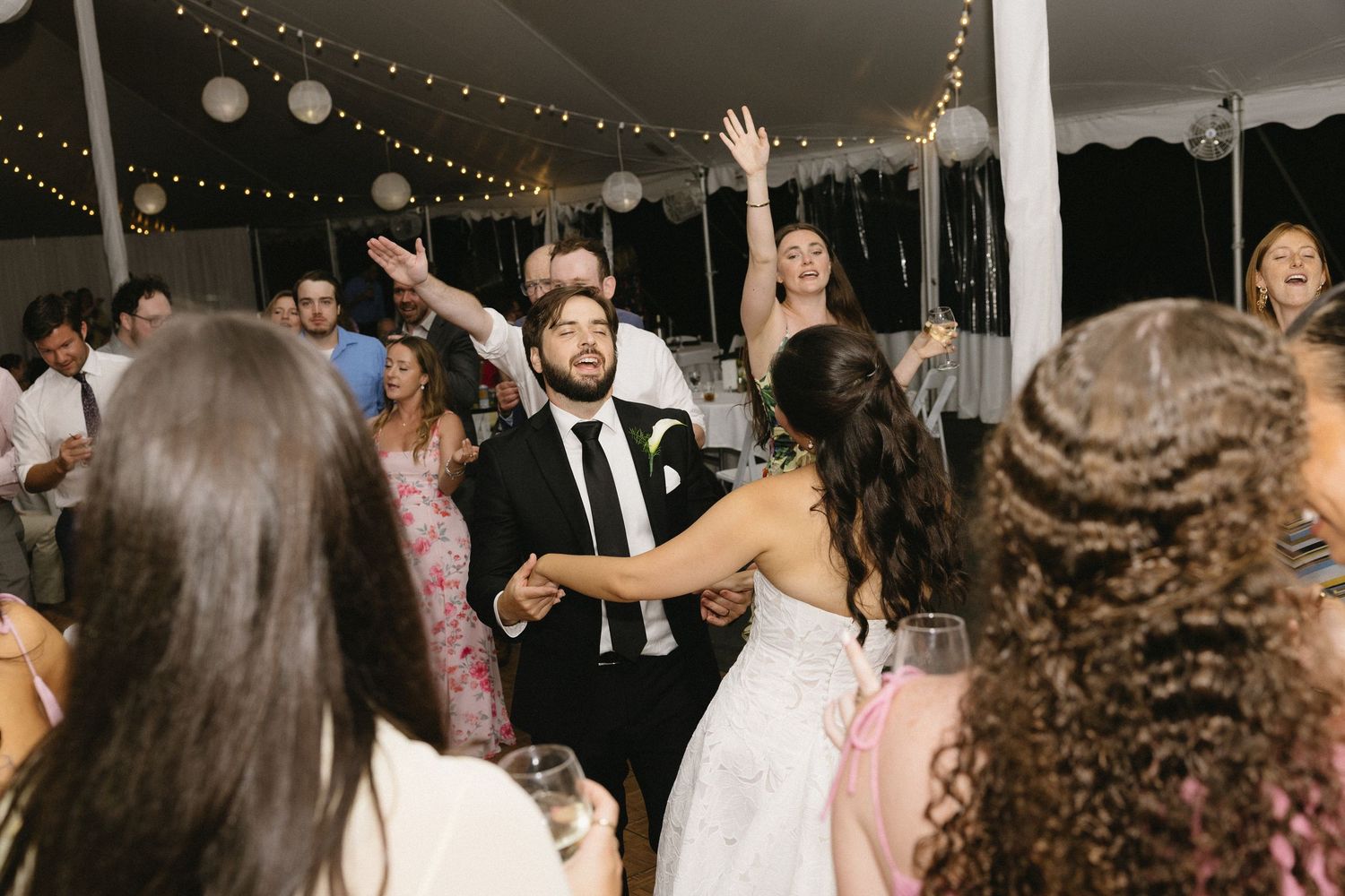 Bride and groom singing on the dance floor under tent string lights at Wadsworth Homestead wedding reception in Geneseo, NY.