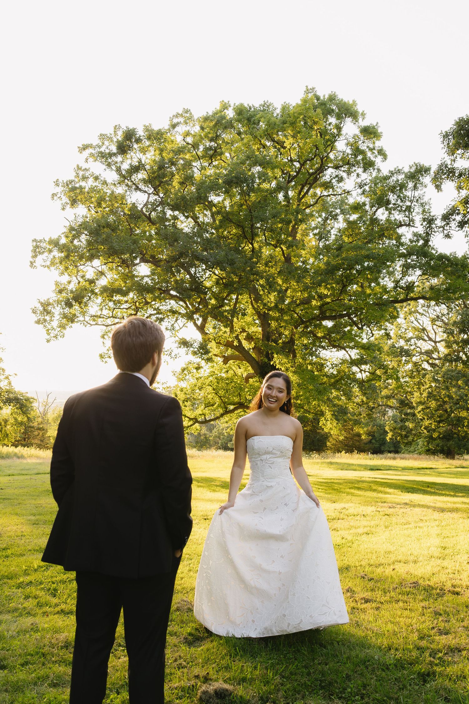 Smiling bride showing off her gown to the groom during golden hour portraits at Wadsworth Homestead in Geneseo, NY.