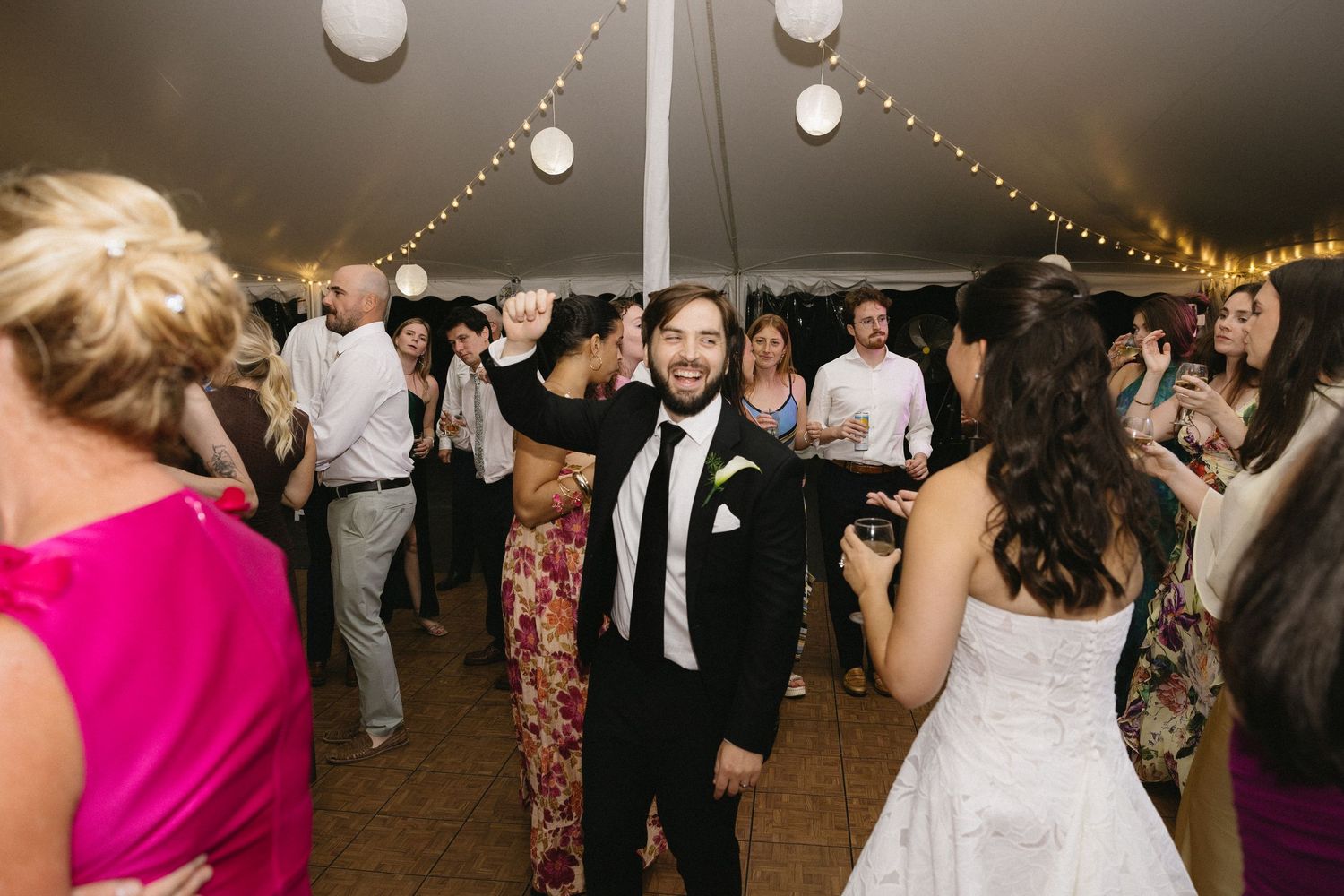 Groom dancing with guests under tent lanterns during a Wadsworth Homestead wedding reception in Geneseo, NY.