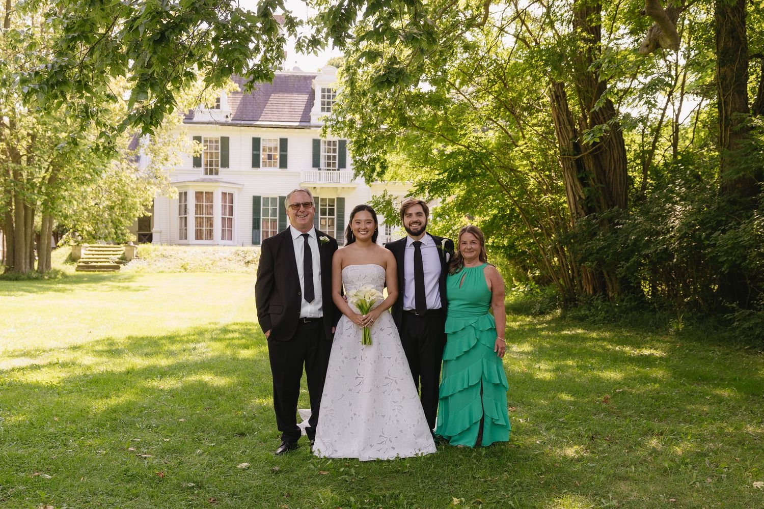 Bride and groom posing with family on the grounds outside Wadsworth Homestead in Geneseo, NY.