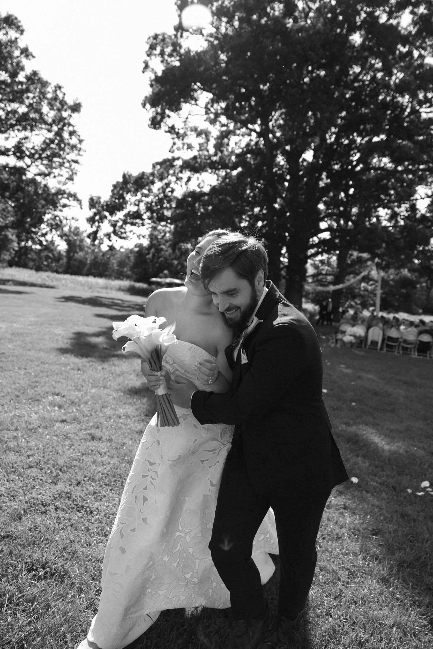 Black and white candid of bride and groom laughing after outdoor ceremony at Wadsworth Homestead in Geneseo, NY.