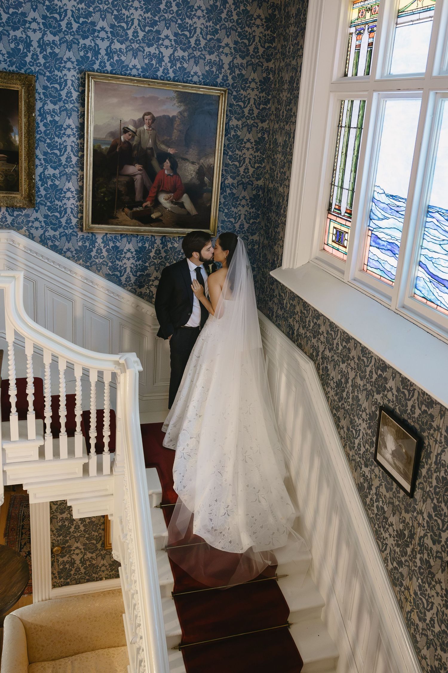 Bride and groom kissing on the grand staircase at Wadsworth Homestead in Geneseo, NY, taken by a Western NY wedding photographer.