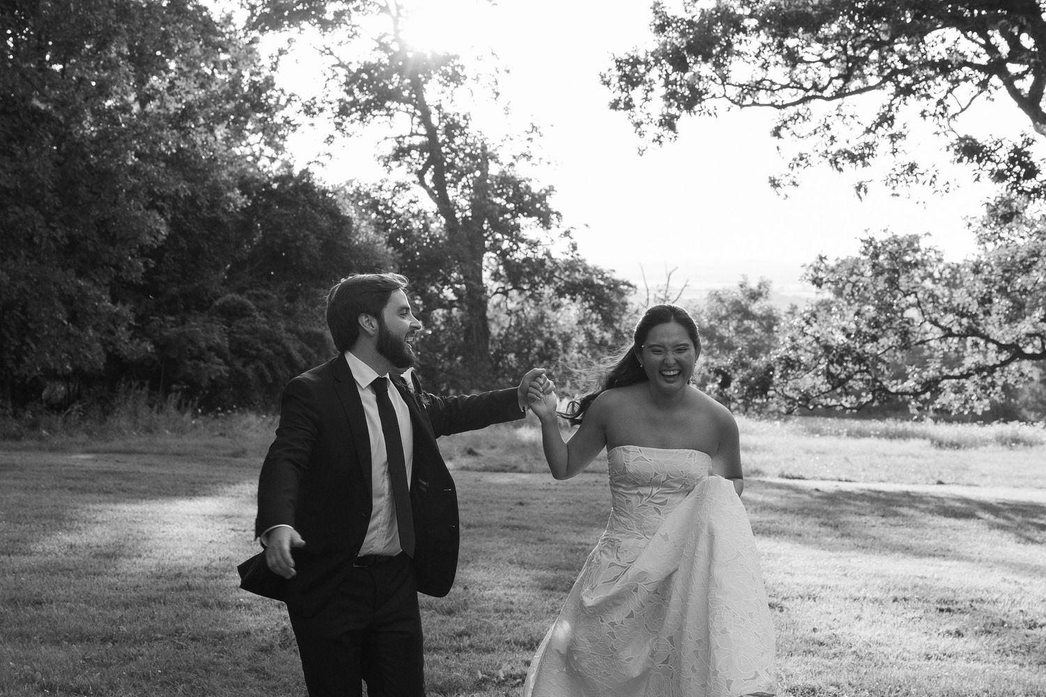Black and white portrait of bride and groom running through a field at Wadsworth Homestead in Geneseo, NY.