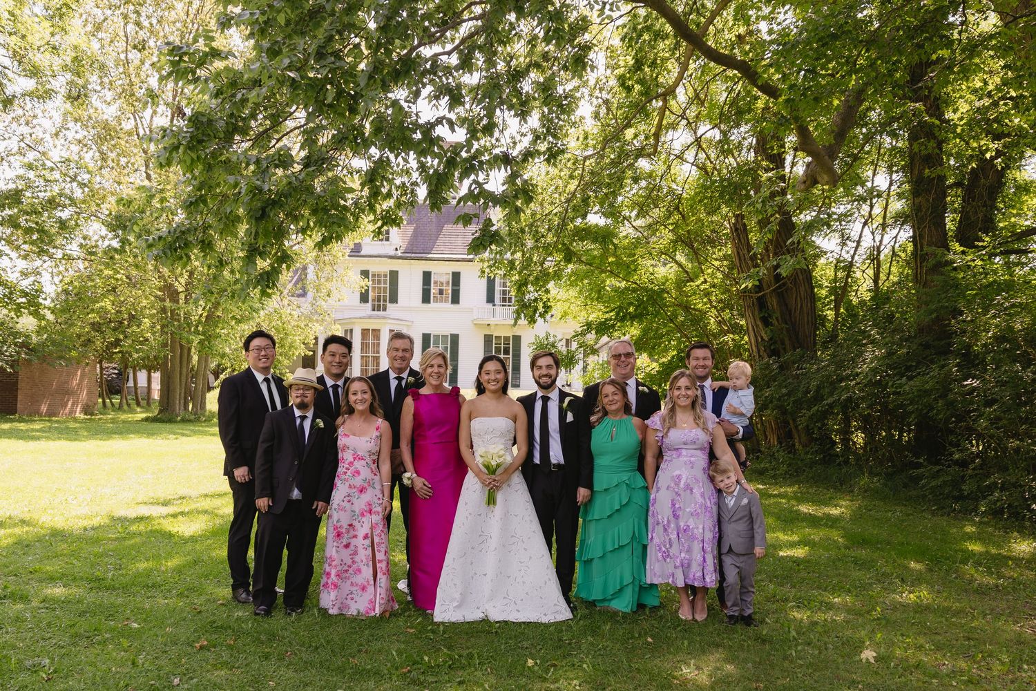 Bride and groom posing with family on the grounds outside Wadsworth Homestead in Geneseo, NY.