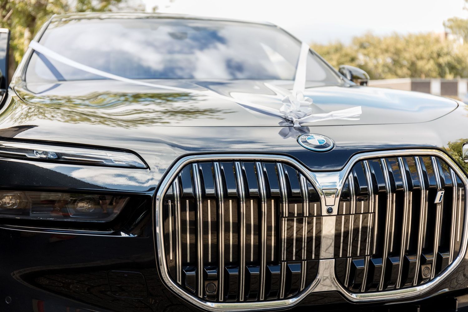Close-up of a sleek black BMW luxury sedan featuring the iconic kidney grille design with chrome accents outdoors.