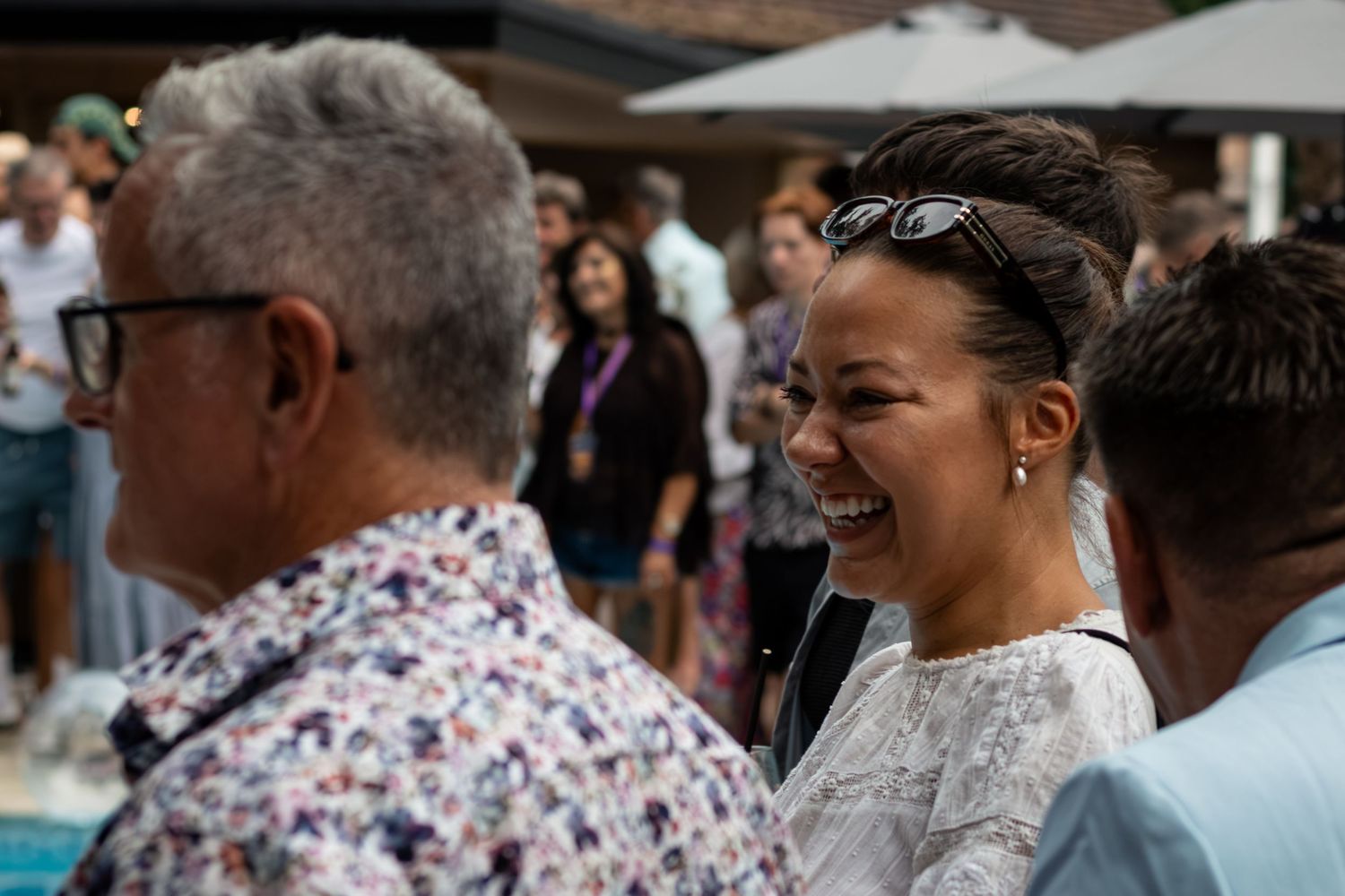 A woman laughing joyfully at an outdoor social gathering event.