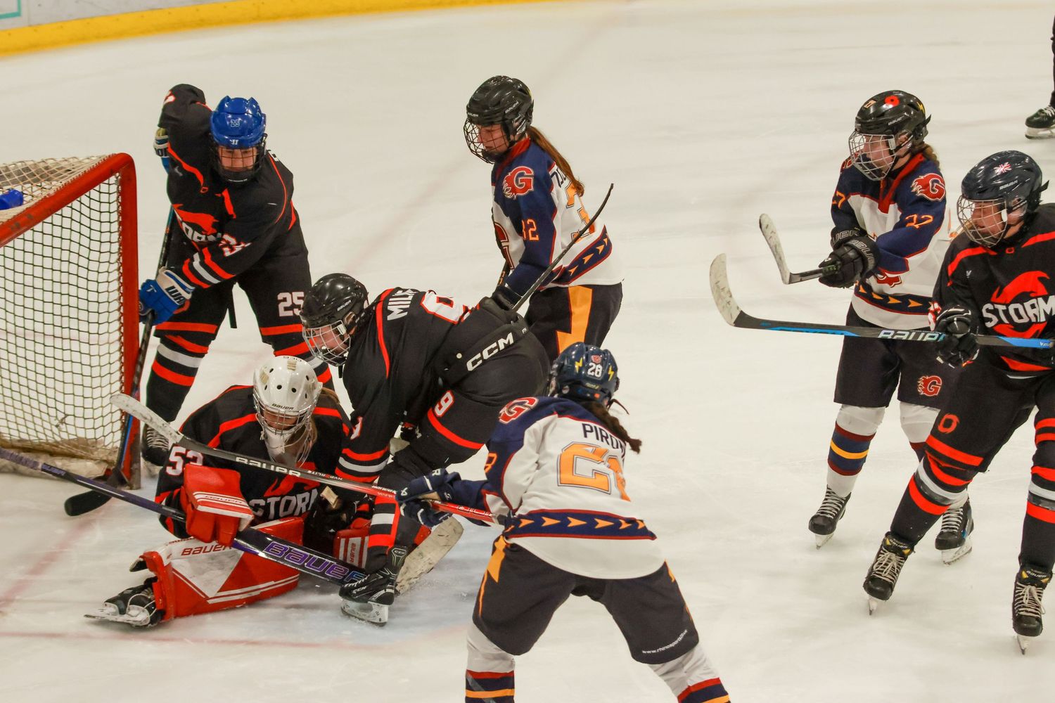 Ice hockey players battle in front of the net during an intense youth hockey game on indoor rink.