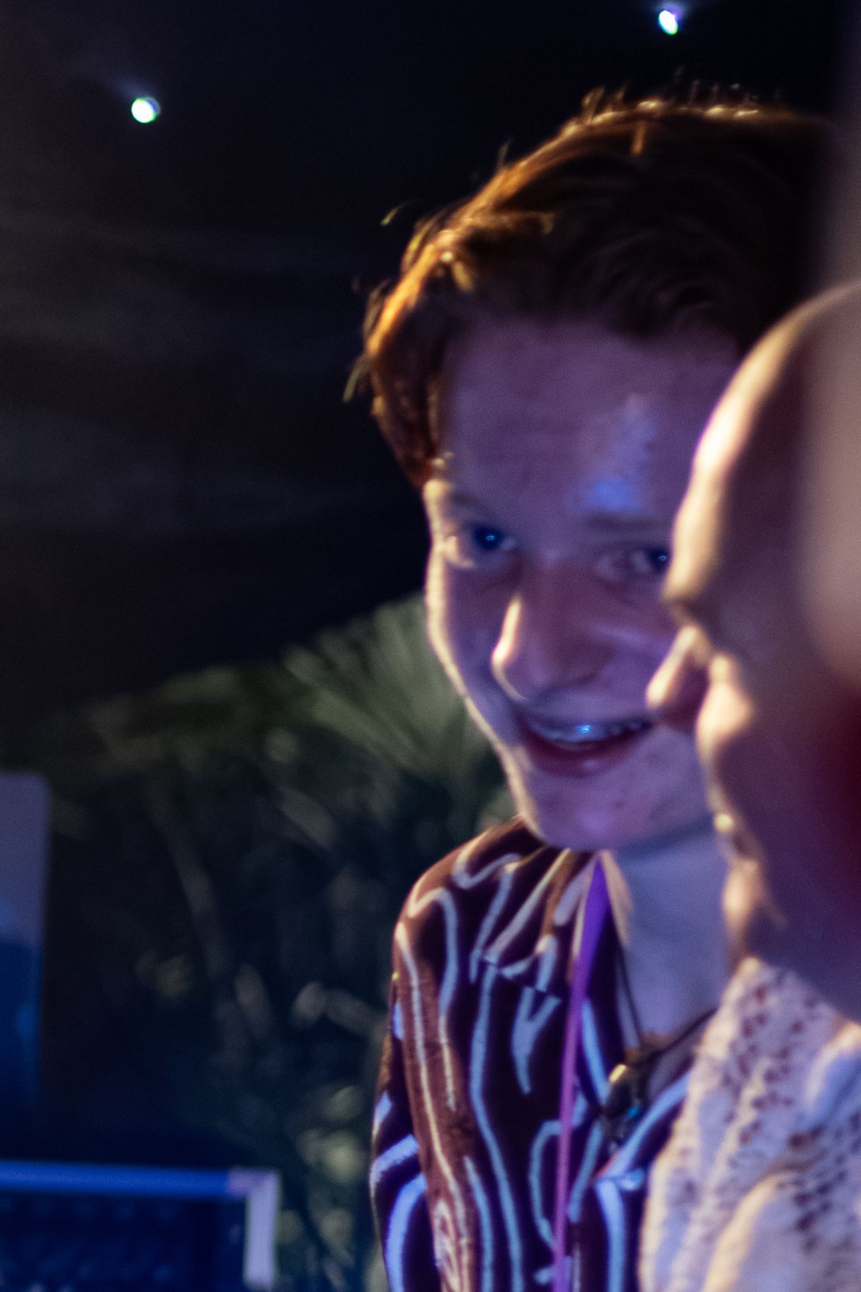 A smiling redhead man at a nighttime outdoor event.