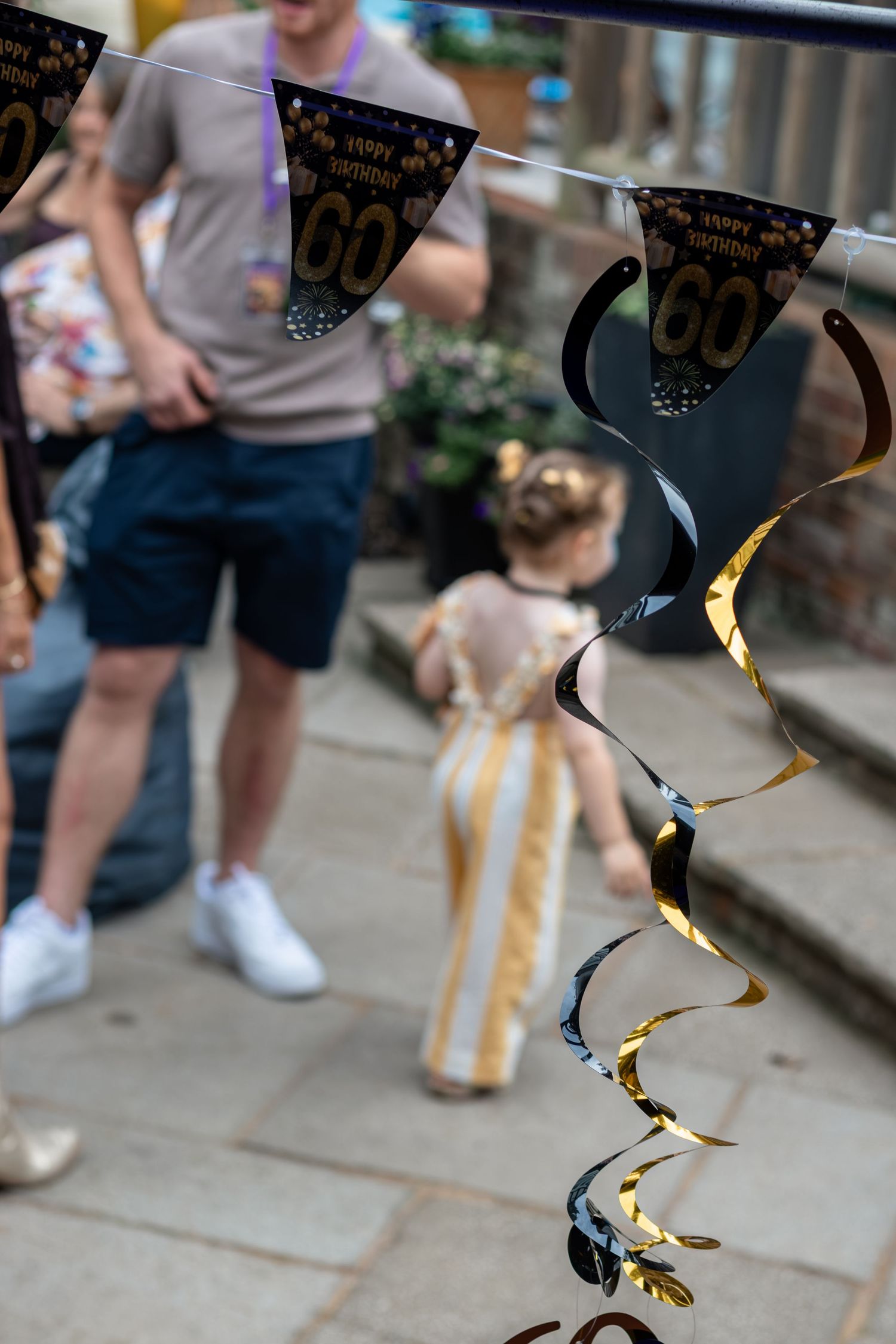 Black and gold 60th birthday bunting decorations with spiral streamers at outdoor party.