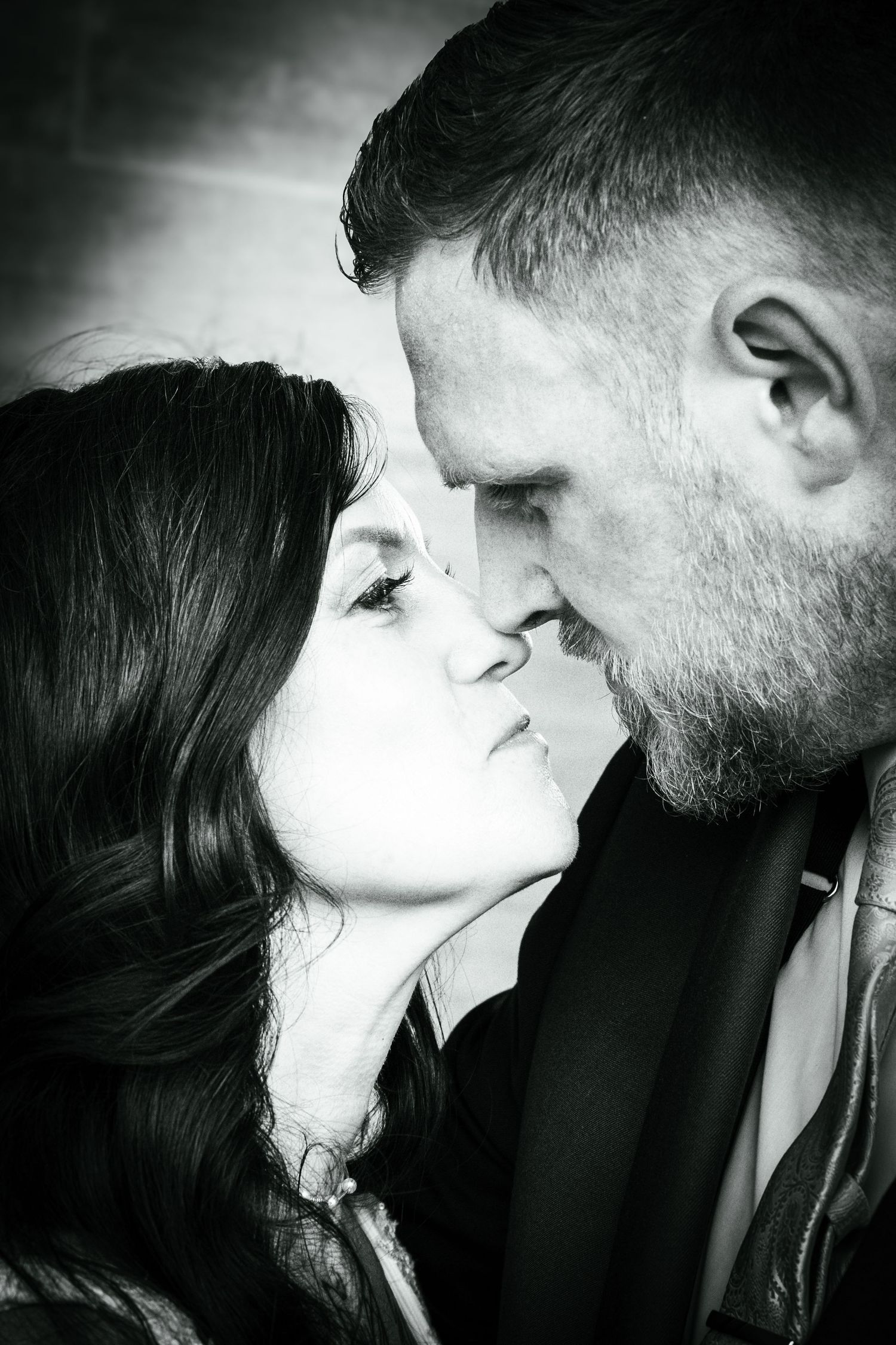 Black and white portrait of a couple sharing an intimate moment, leaning in close for a kiss.