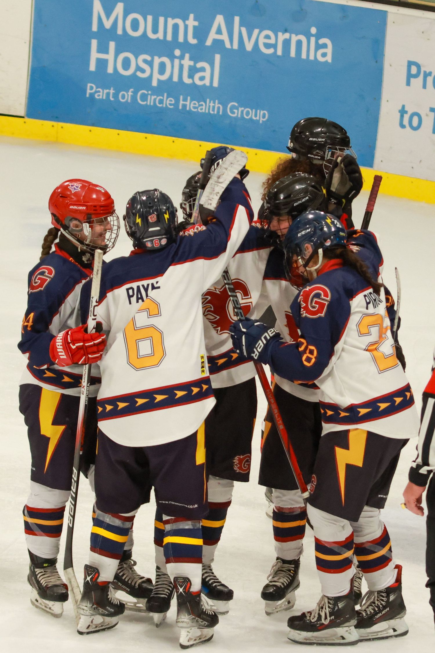 Guildford Flames ice hockey players huddle in celebration near the Mount Alvernia Hospital rink boards.