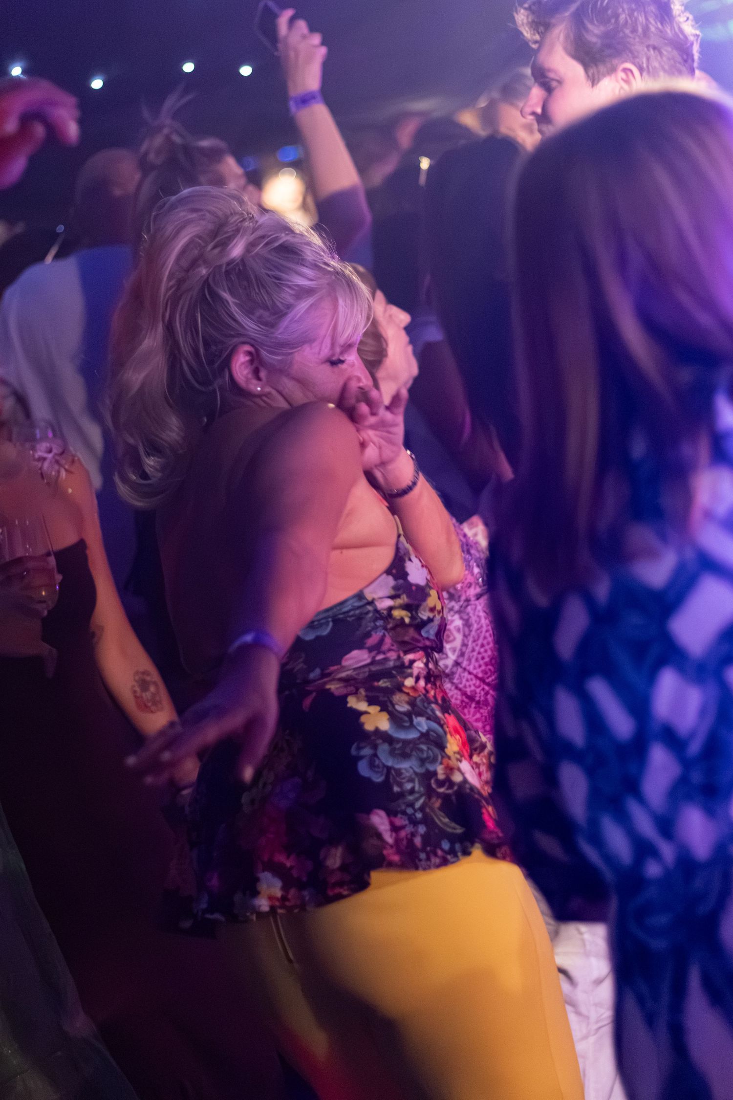 People dancing energetically at a nightclub party under purple lights.