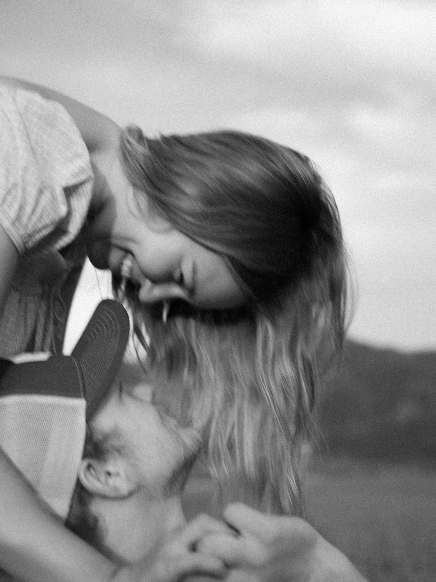 Black and white romantic close-up of couple sharing an intimate moment in an open field.