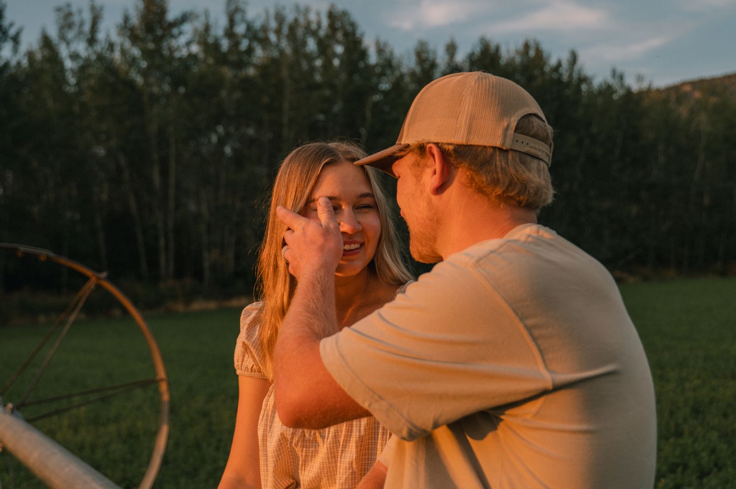 Man gently touching a smiling womans face during a sunset outdoor photo session.