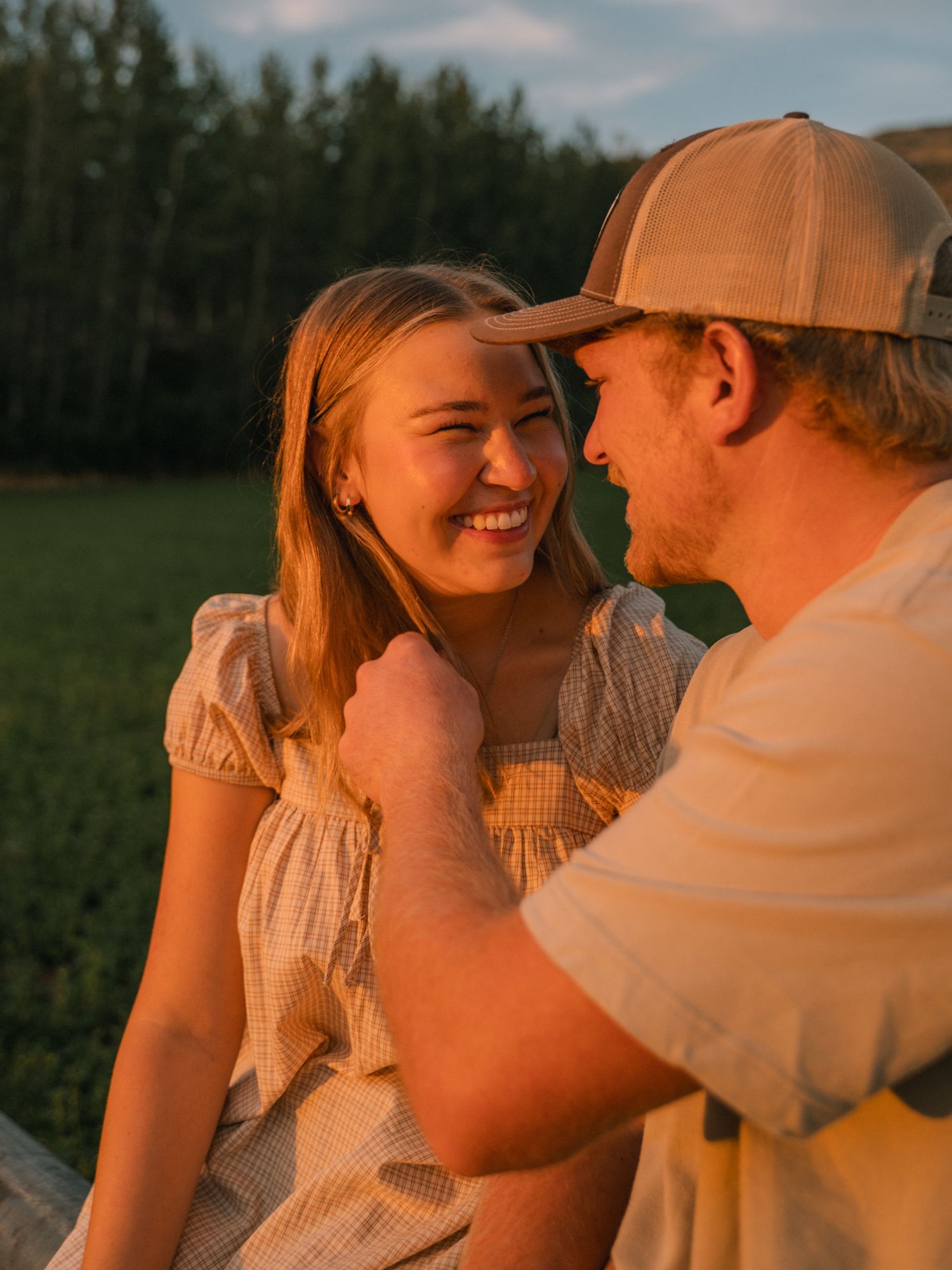 Smiling couple sharing a tender moment together sitting outdoors at golden hour sunset.