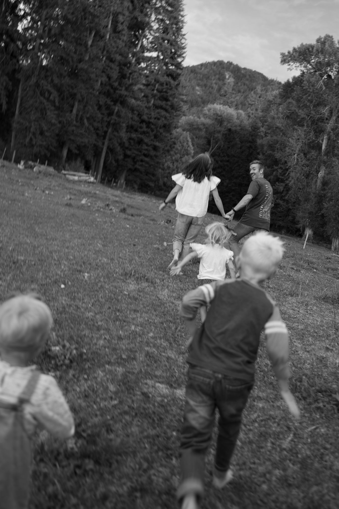 Black and white photo of a family running together in a grassy outdoor setting.