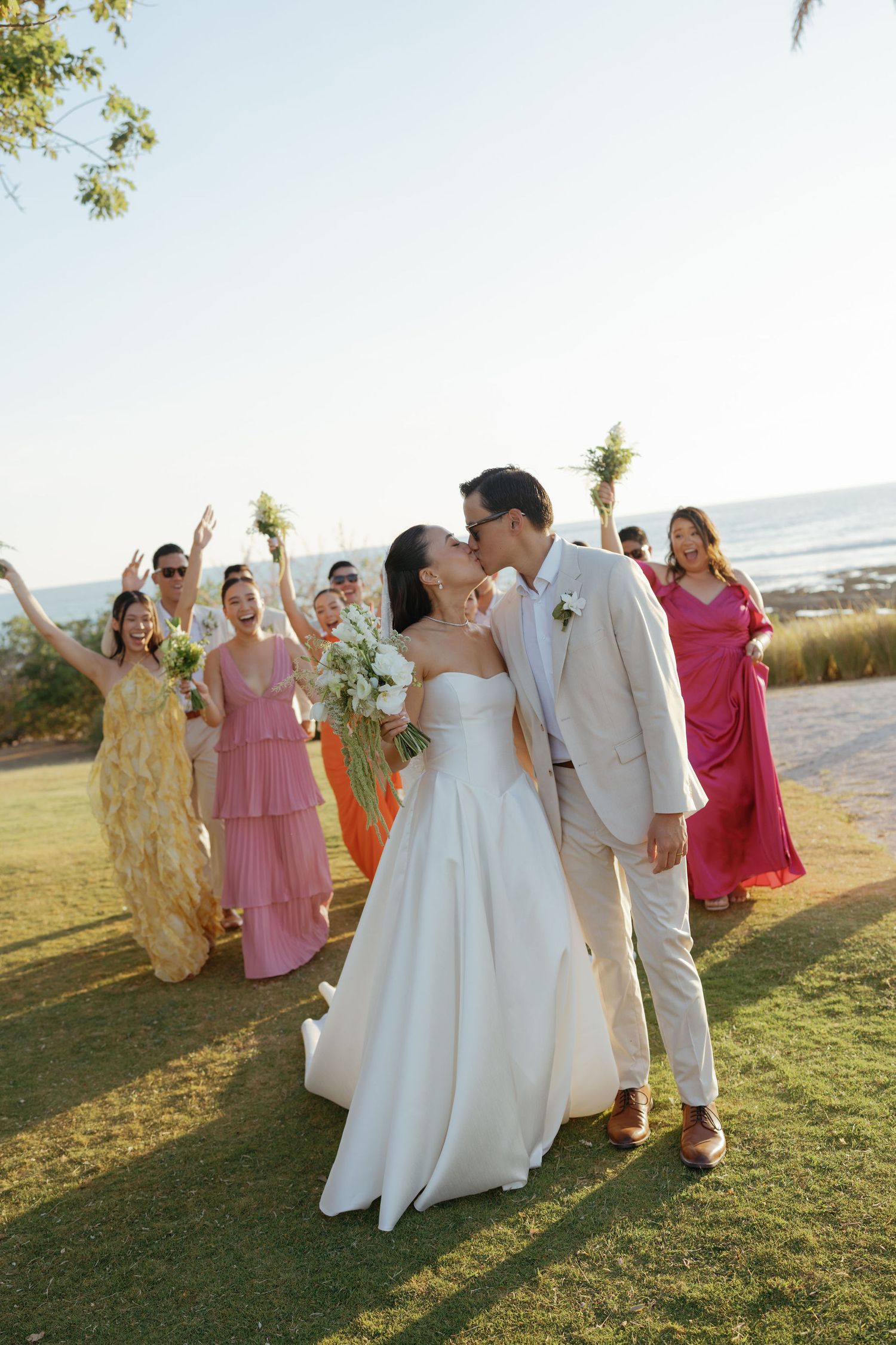 Ashley and Ryan kissing with their wedding party celebrating behind them at Hacienda Pinilla
