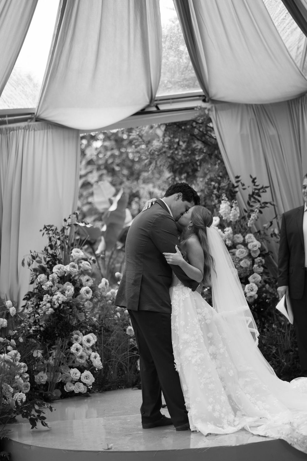 Maureen and Major sharing a kiss during their wedding ceremony surrounded by floral arrangements in Costa Rica