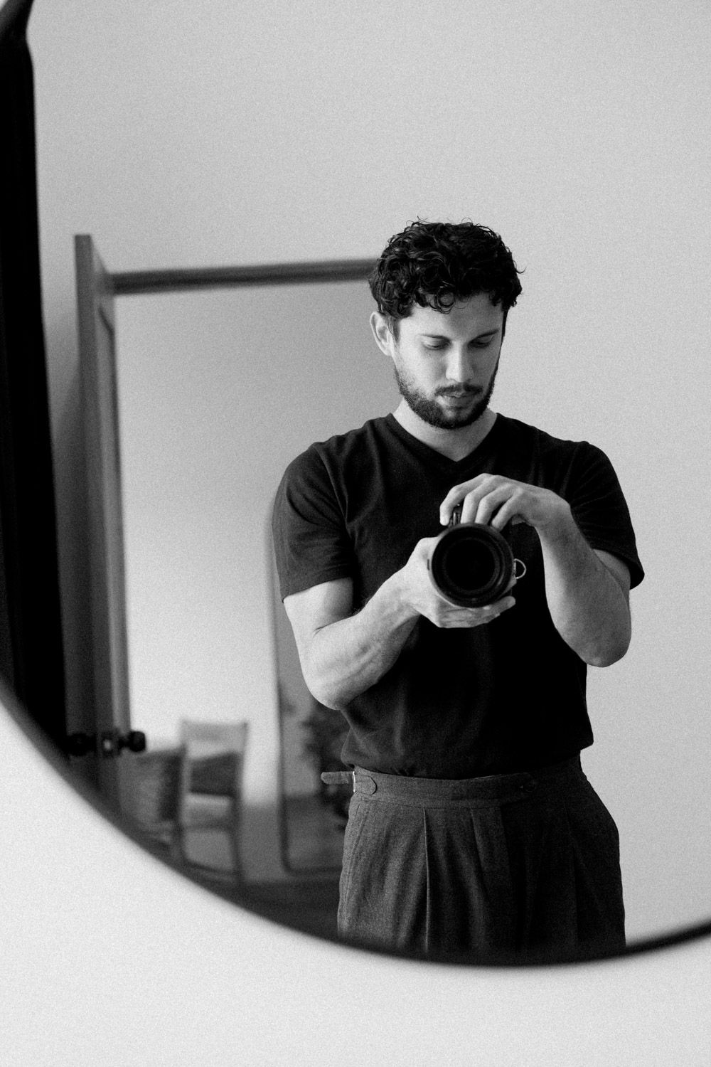 Black-and-white mirror portrait of Costa Rica wedding photographer Javier Mendez holding his camera.