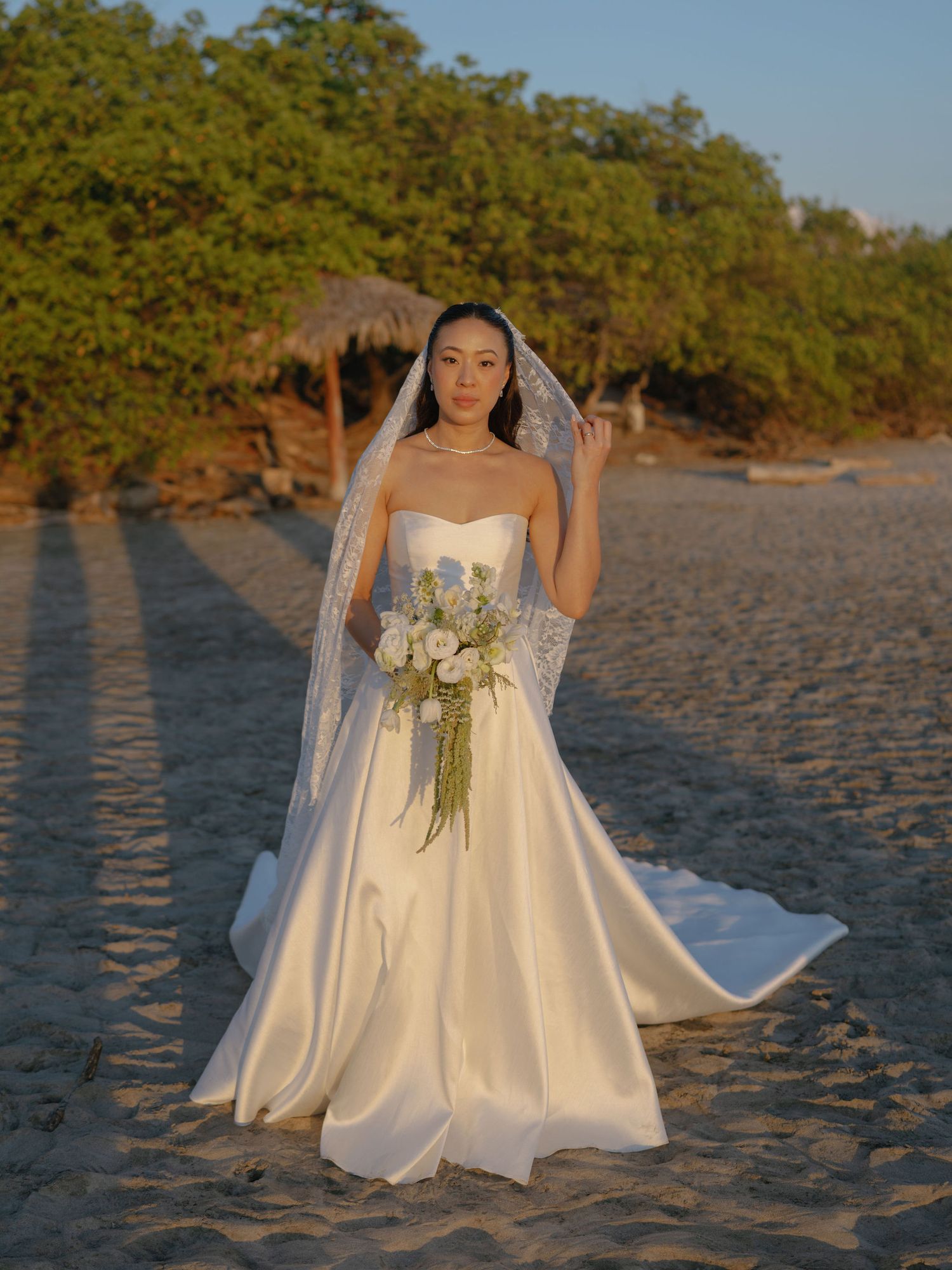Ashley holding her bouquet during a golden hour bridal portrait on the beach at Hacienda Pinilla