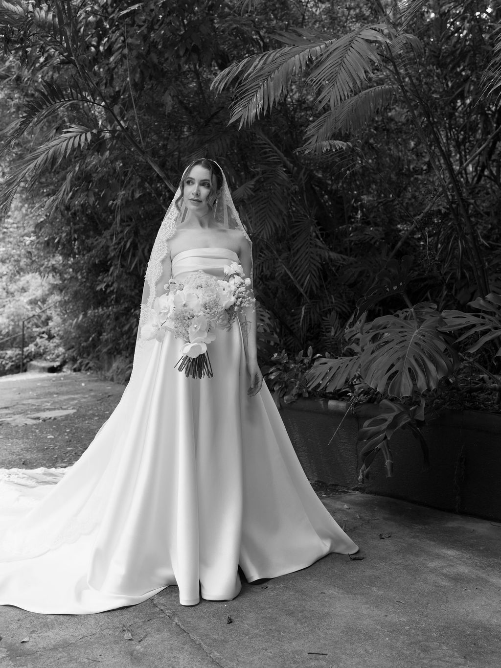 Bride in a satin wedding gown surrounded by tropical greenery in Monteverde