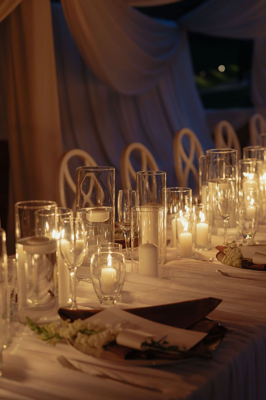 Close-up of glowing candles and glassware decorating a wedding dinner table in Monteverde