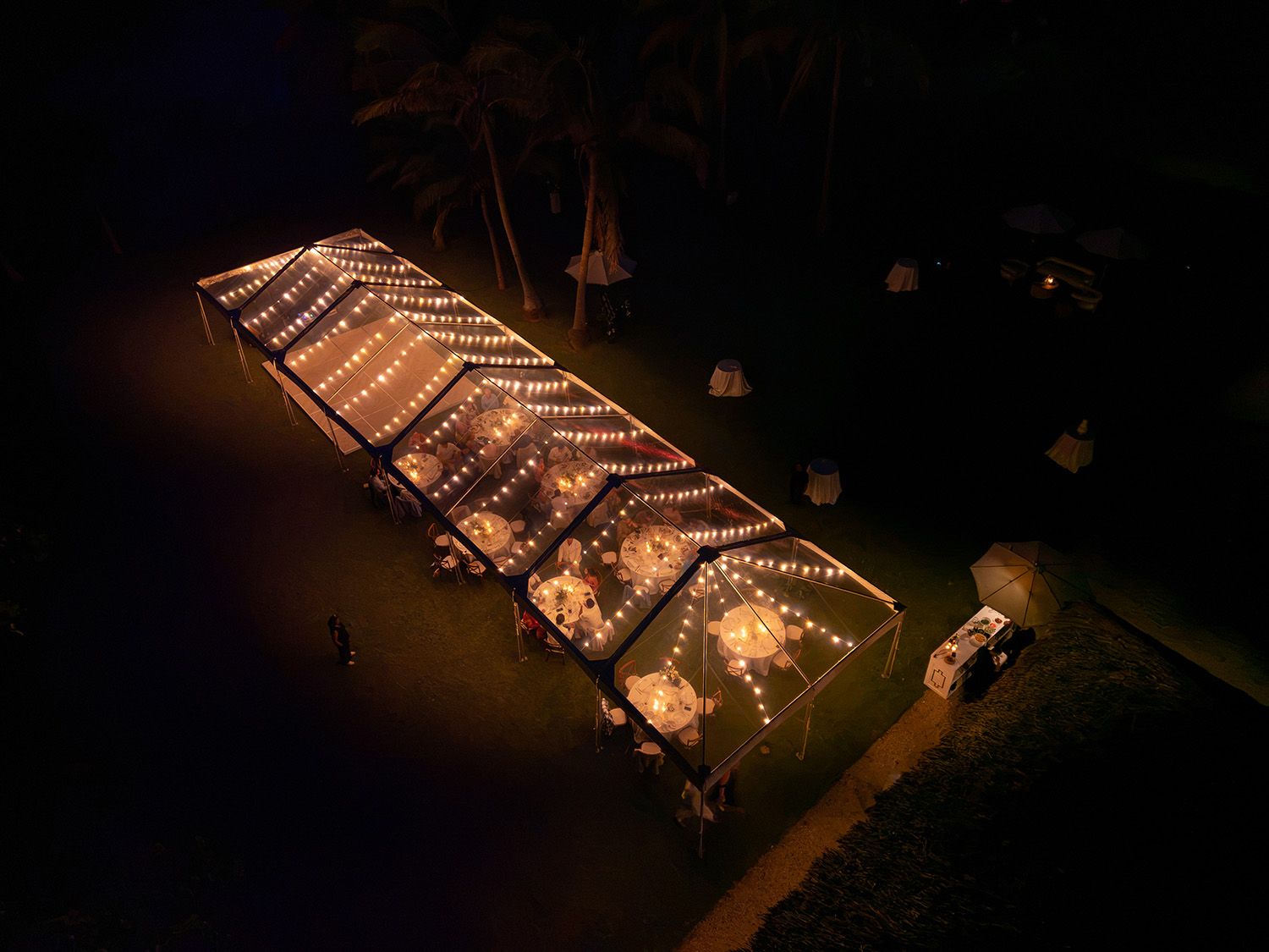 Aerial view of an illuminated outdoor wedding reception in Costa Rica at night.