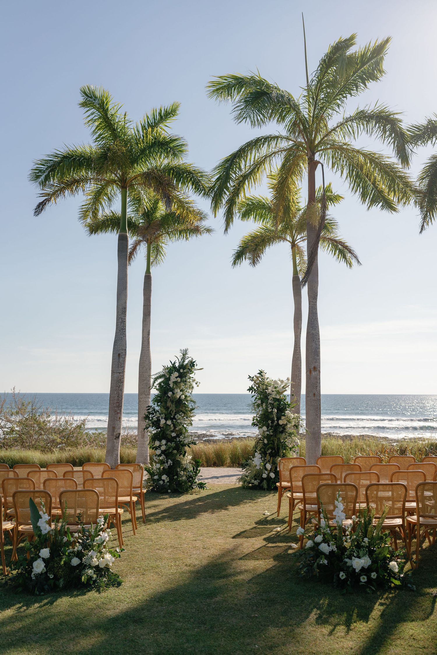 Beachfront wedding ceremony setup with palm trees and white flowers at Hacienda Pinilla in Costa Rica