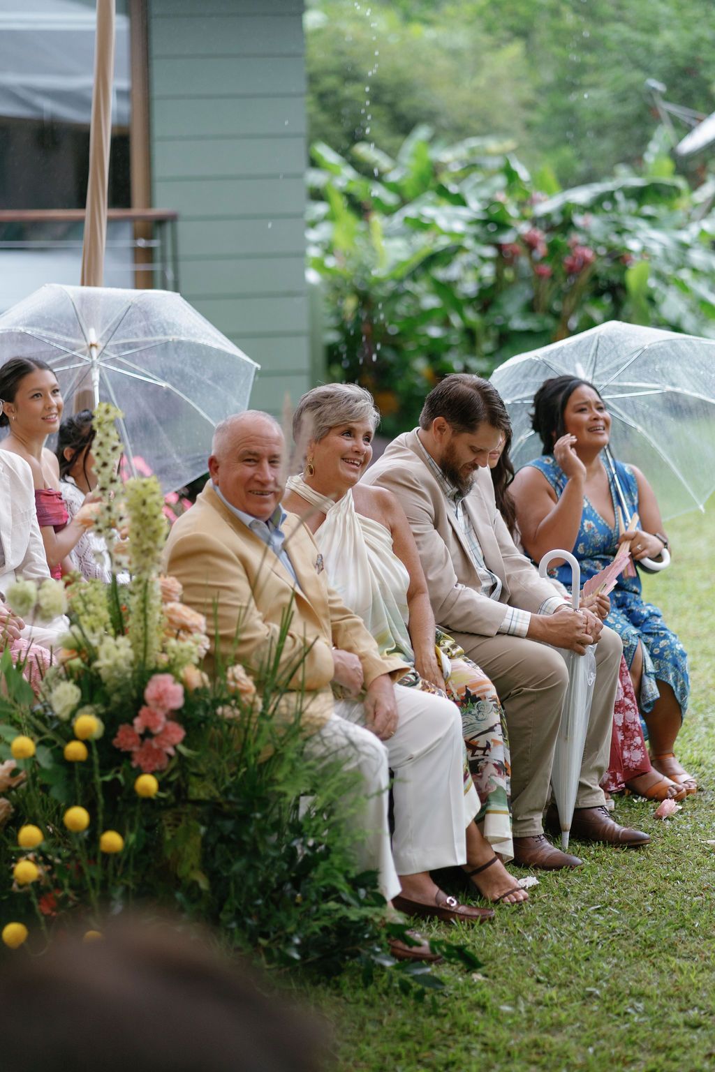 Wedding guests seated beneath umbrellas during a rainy rainforest ceremony in Costa Rica