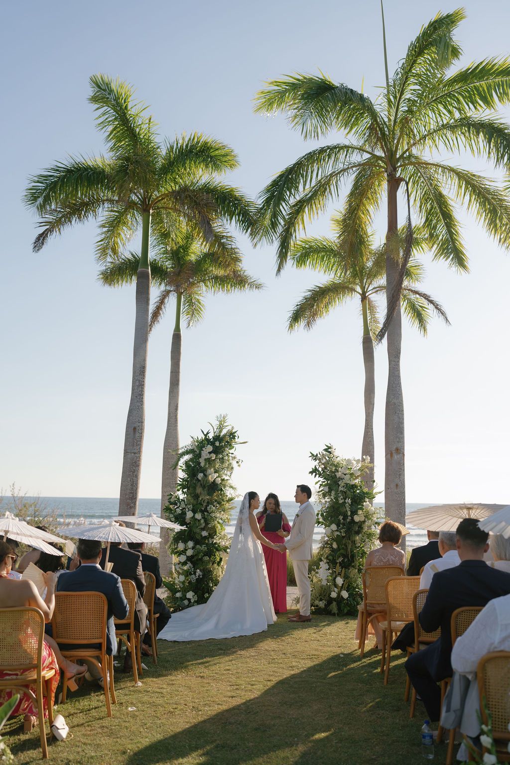 Bride and groom exchanging vows beneath palm trees at a beach wedding in Costa Rica.