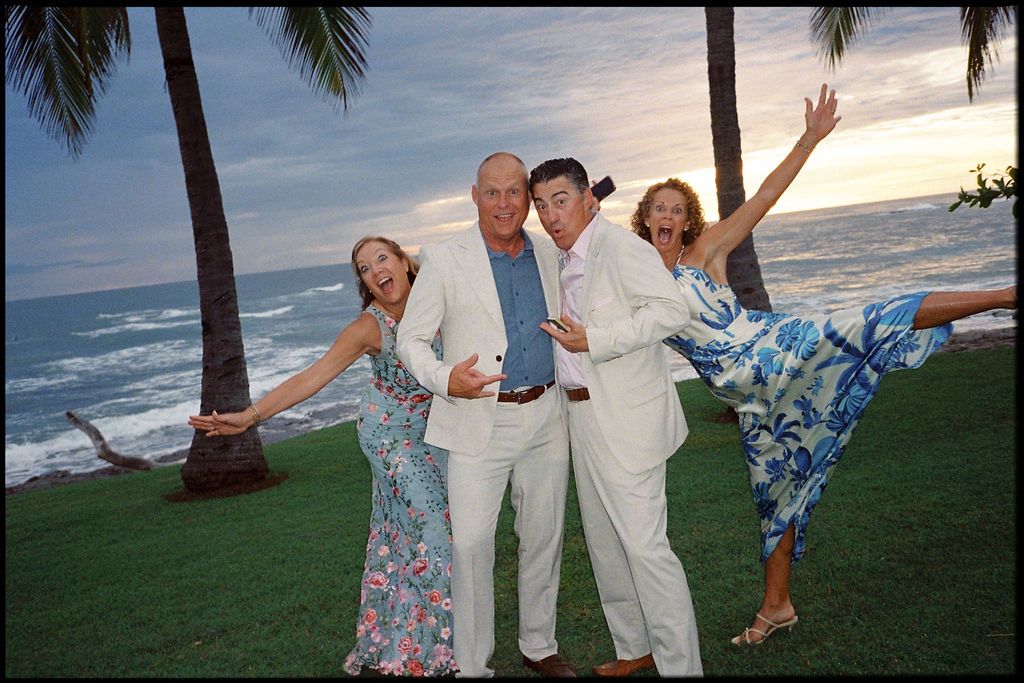 Four wedding guests posing playfully beside the ocean at sunset in Costa Rica.