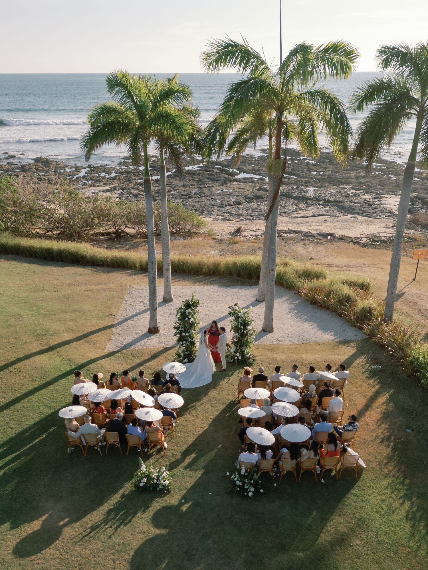 Aerial view of an oceanfront wedding ceremony surrounded by palm trees at Hacienda Pinilla