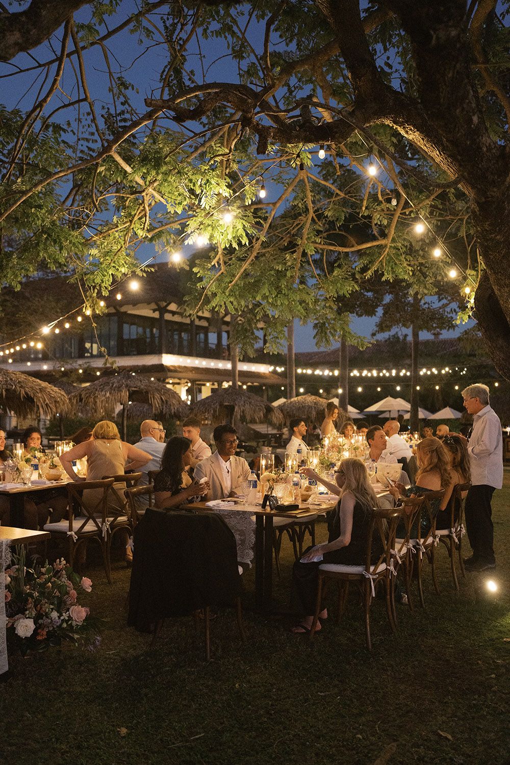 Guests dine at long candlelit tables under a tree in hacienda Pinilla