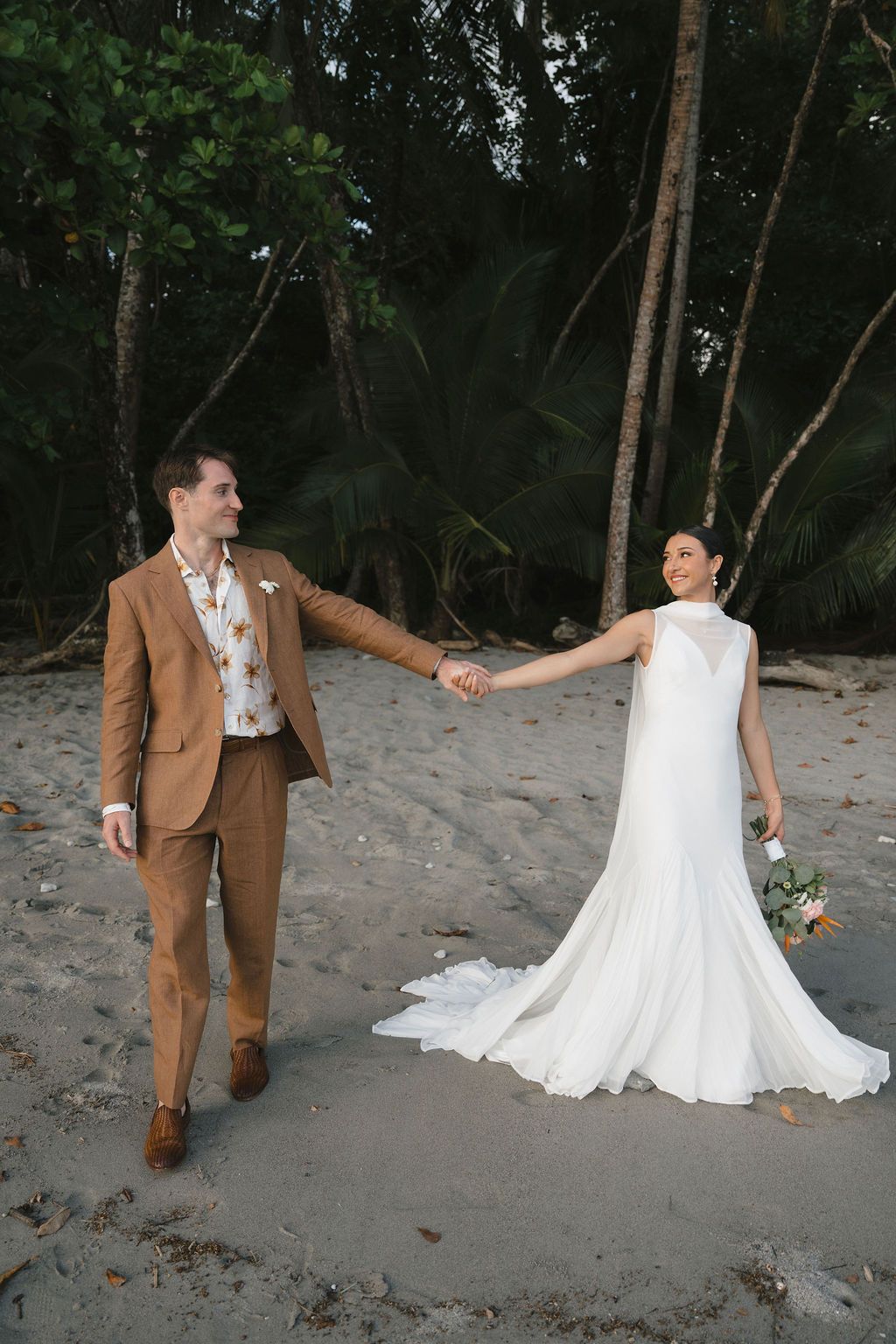 Couple holding hands beside the tropical forest during their intimate Costa Rica wedding.