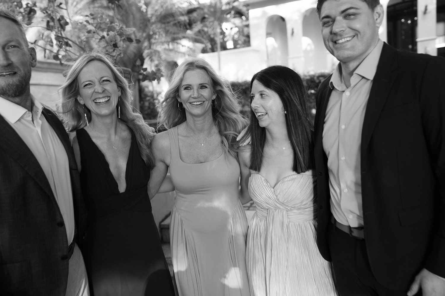 Black-and-white photograph of five wedding guests smiling and laughing together outdoors in Costa Rica.