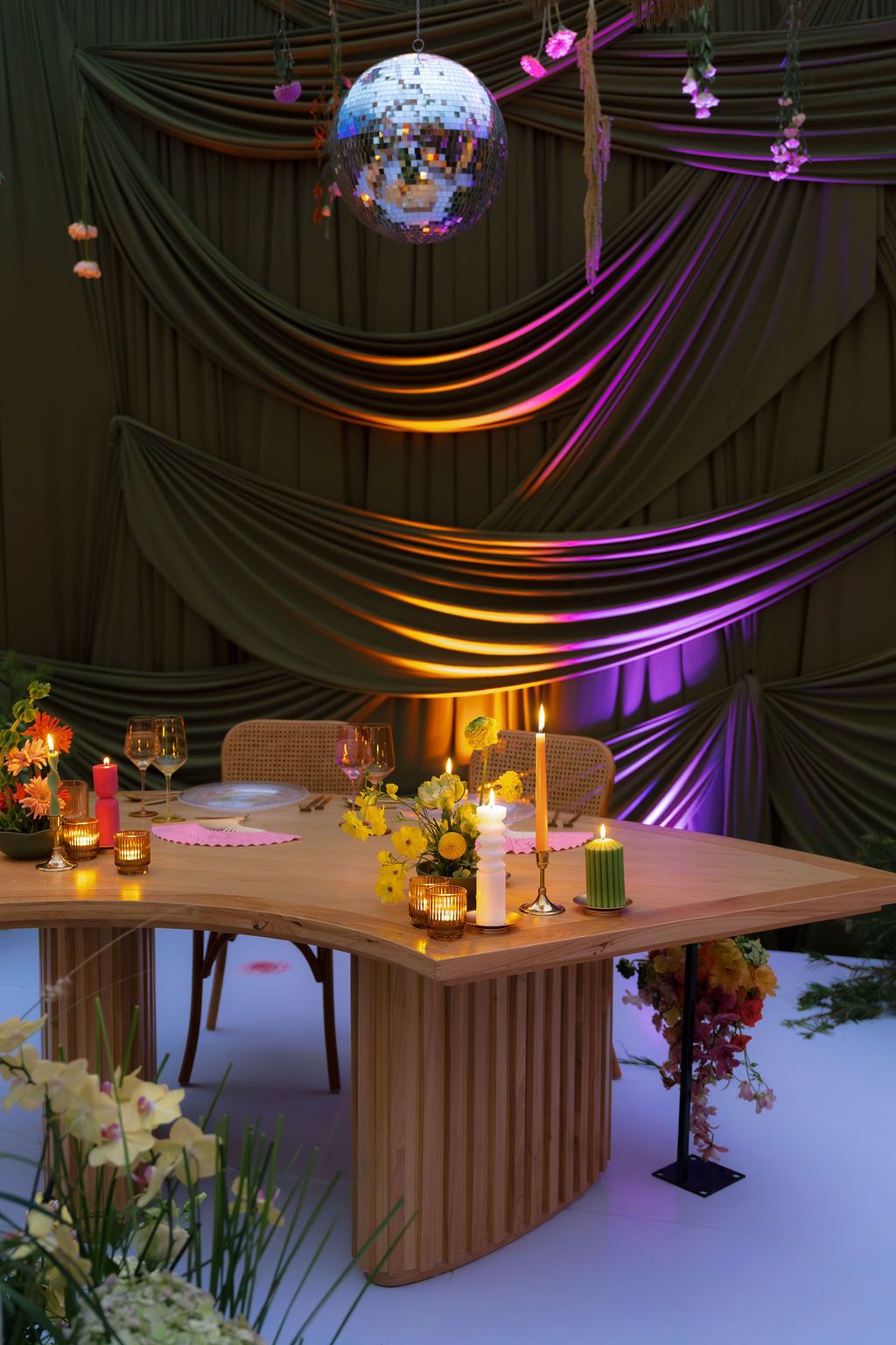 Colorful wedding reception table with candles, florals, disco ball, and green draping in Costa Rica