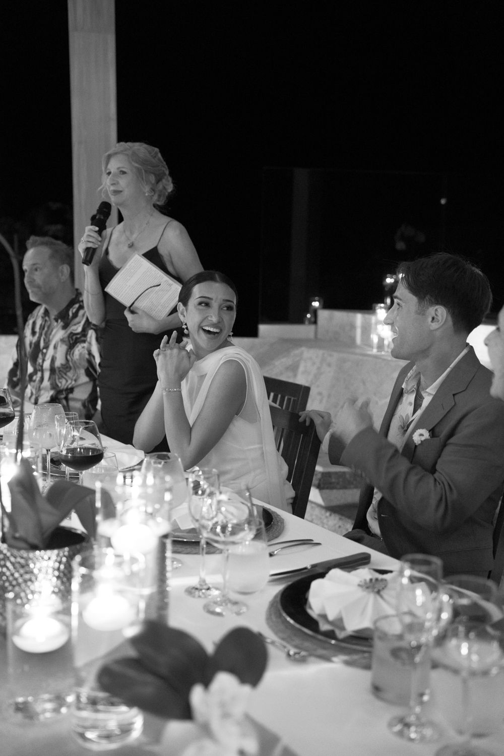 Sadie smiles while listening to a speech at her candlelit wedding dinner.