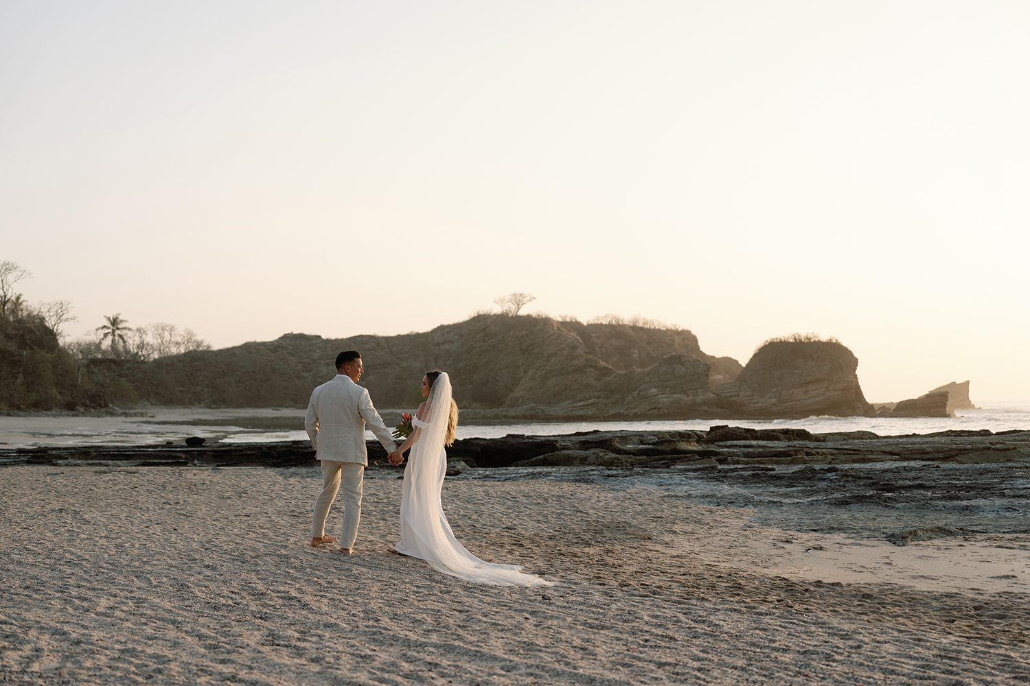 Newlyweds walking together along the beach at sunset after their Costa Rica wedding.