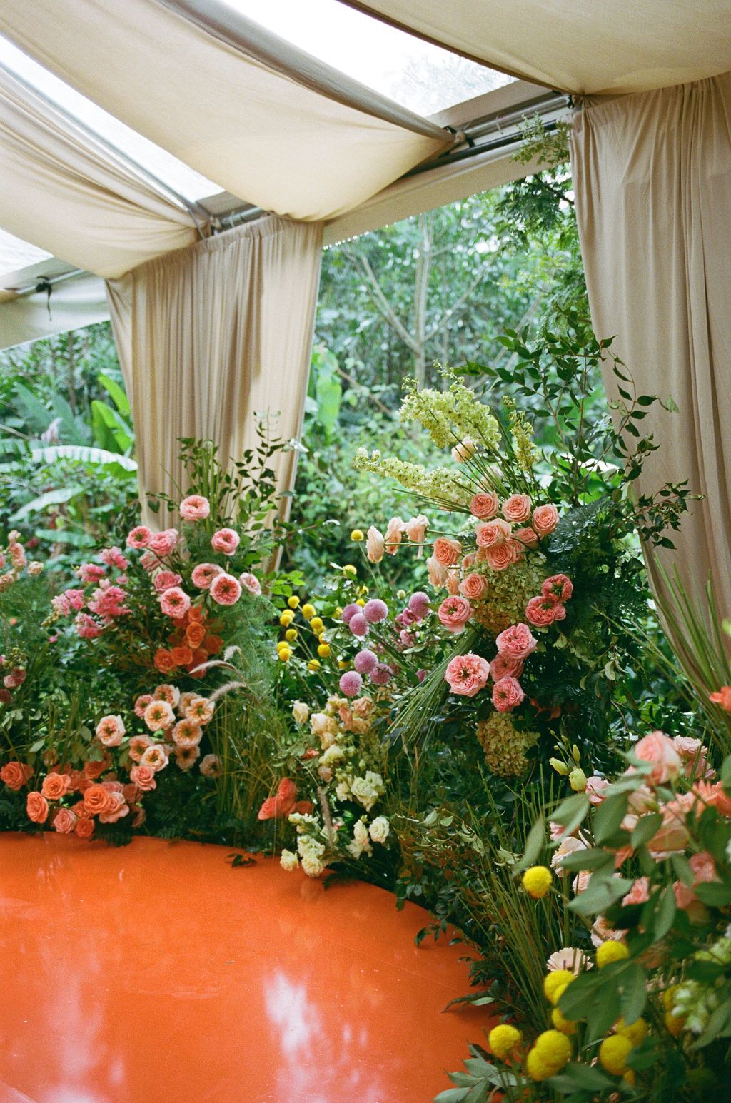 Colorful floral ceremony installation surrounded by rainforest at a Costa Rica wedding photographed on film