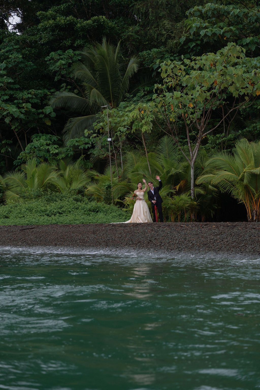 Anita and Maclean waving from the secluded shoreline of Golfo Dulce Retreat
