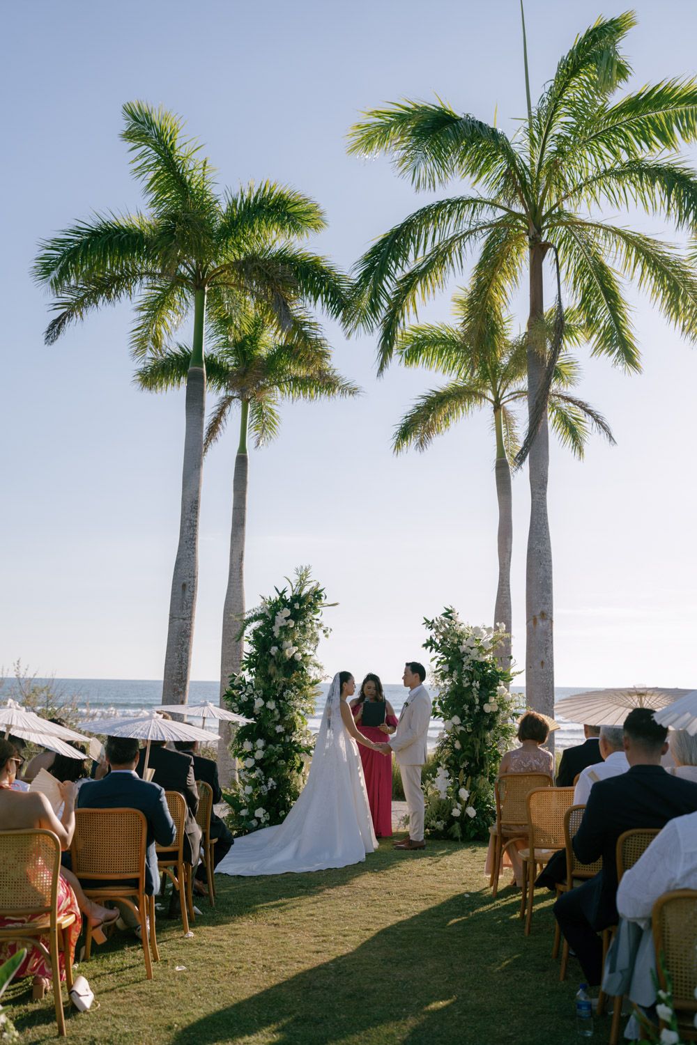 Outdoor beach wedding ceremony with couple exchanging vows under palm trees in costa rica