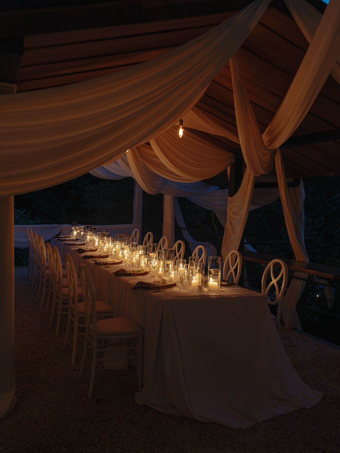 wedding reception table beneath flowing fabric drapes at an evening celebration in Costa Rica.