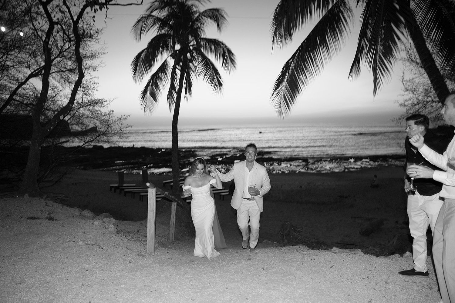 Wedding guests walking from the beach during a candid black and white moment in Costa Rica.