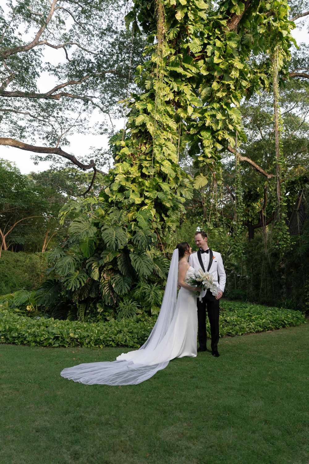 Bride and groom stand together during outdoor garden wedding ceremony.