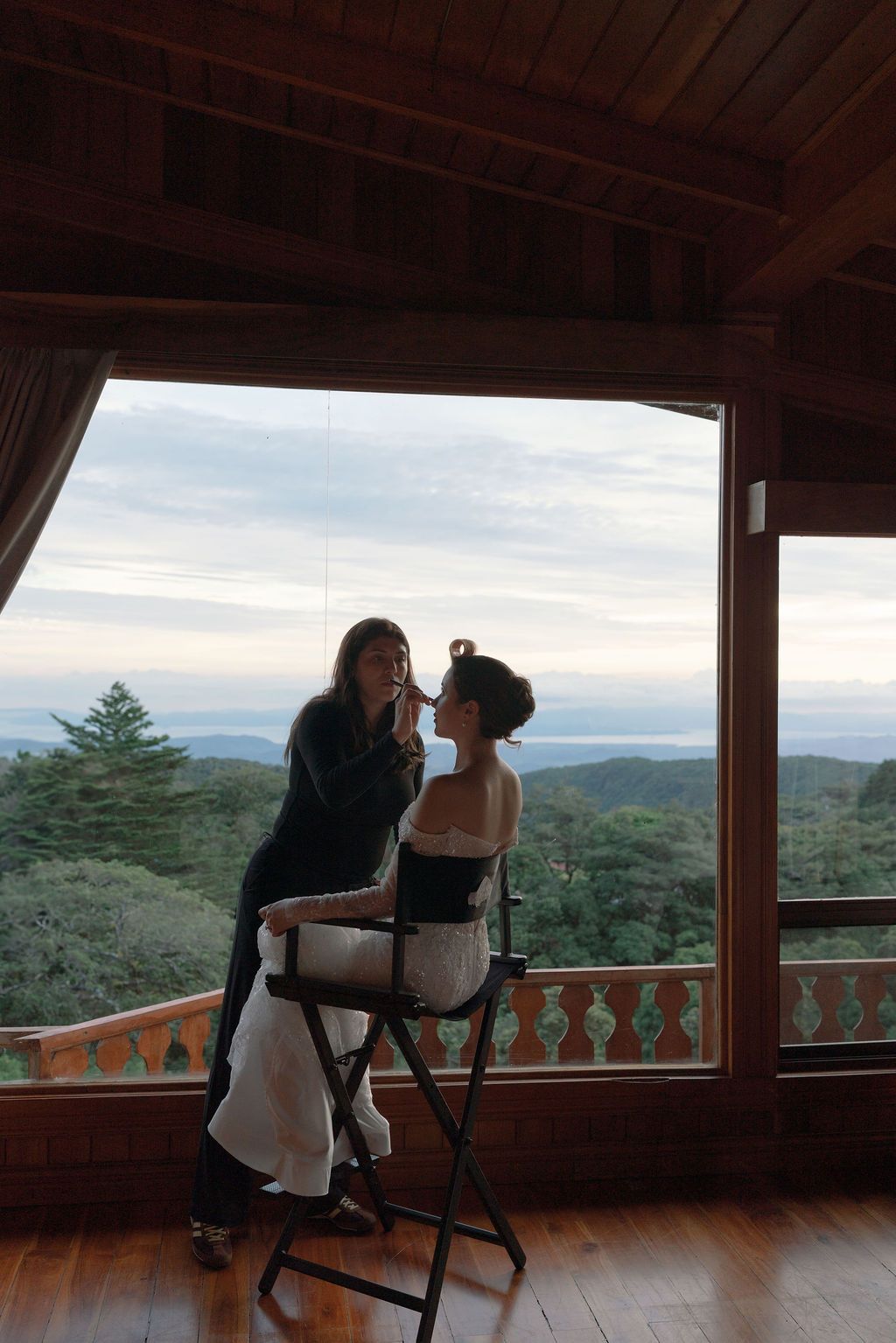 Bride having her makeup done beside a window overlooking the mountains of Monteverde
