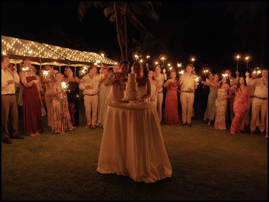 Wedding guests holding sparklers around Morgan and Britton as they cut their cake