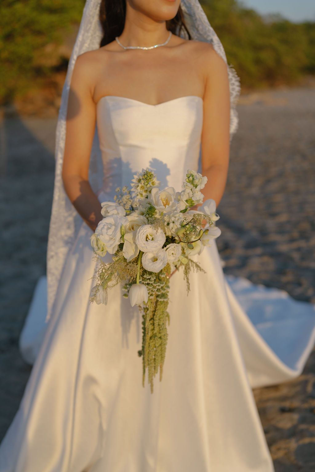 Bride holding a white floral bouquet in warm golden-hour light during her Costa Rica wedding.